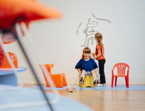 Ein Kind sitzt auf einem Kinderstuhl.