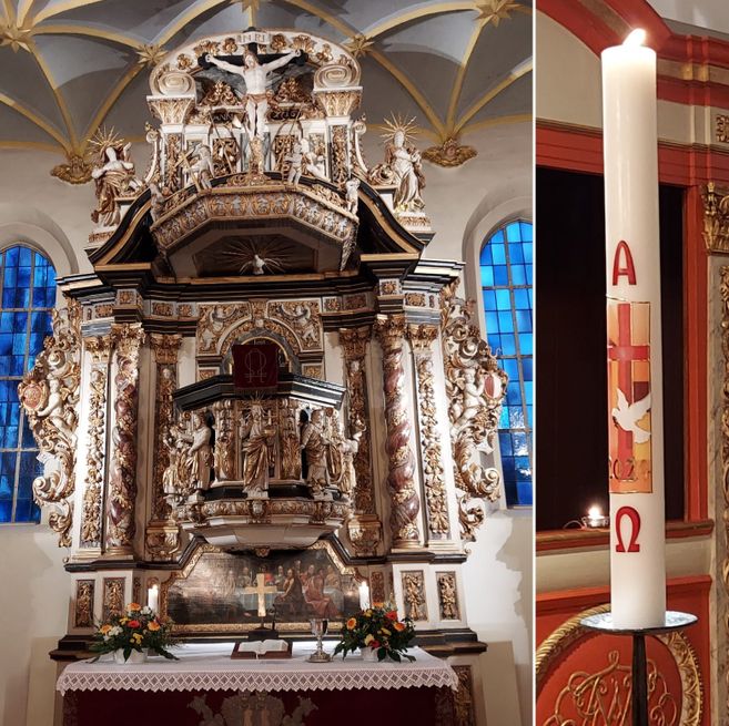 Ein reich verzierter Altar in einer Kirche mit einer großen Taufkerze daneben.