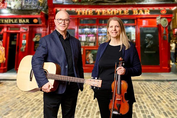 Zwei Musiker vor der Temple Bar in Dublin, Irland, mit Gitarre und Geige.
