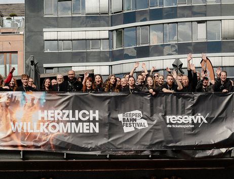 Gruppe von Menschen steht hinter einem Banner mit der Aufschrift 'Herzlich Willkommen' beim Reeperbahn Festival.