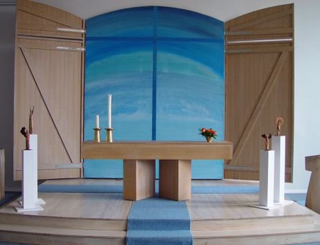Innenansicht einer Kirche mit Altar, Kerzen und blauer Wanddekoration.