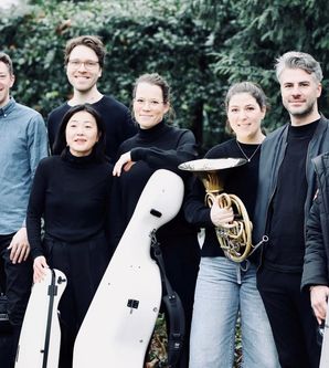 Gruppe von acht Personen mit Musikinstrumenten im Freien.