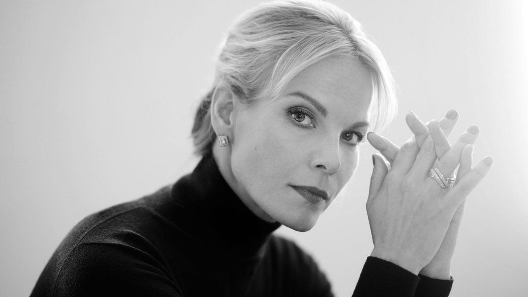 Schwarz-weiß Porträt einer Frau mit blonden Haaren, die nachdenklich in die Kamera schaut.