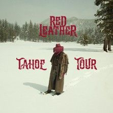 Person in langem Mantel und rotem Hut steht im Schnee, umgeben von Bäumen und Bergen. Text: Red Leather - Tahoe Tour.