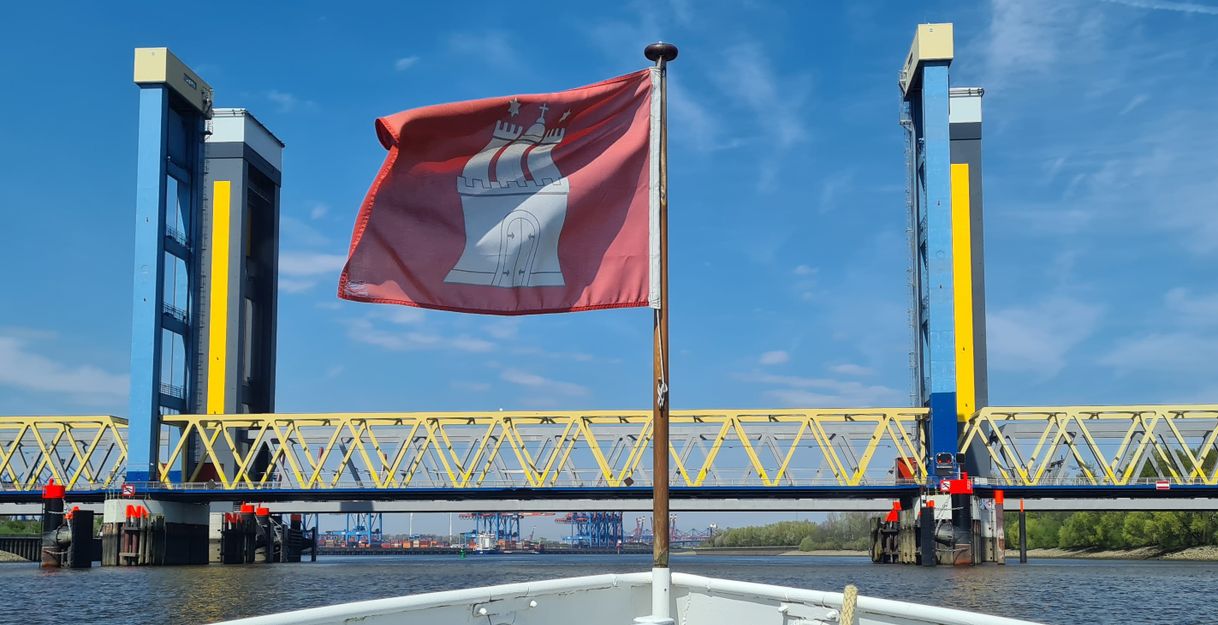 Am Bug eines Schiffs flattert eine Hamburg-Fahne, während das Schiff auf die Kattwykbrücken zusteuert.