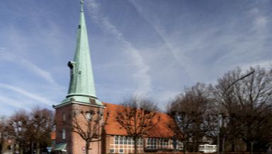 Kirche St. Johannis in Hamburg-Eppendorf mit spitzem Turm und rotem Dach.