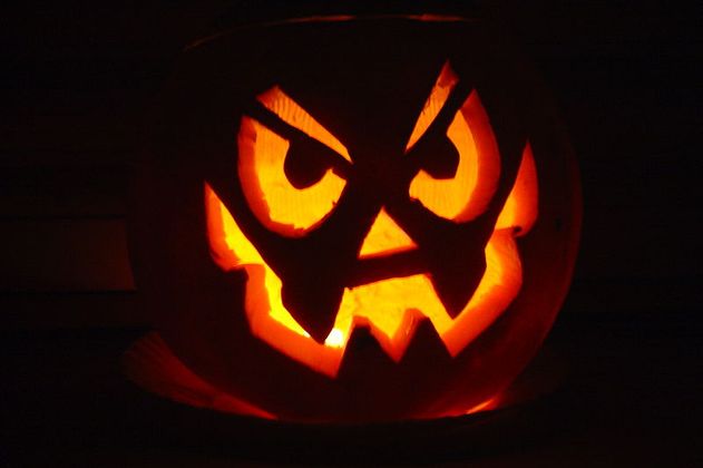 Ein beleuchteter Kürbis mit grimmigem Gesicht, typisch für Halloween.