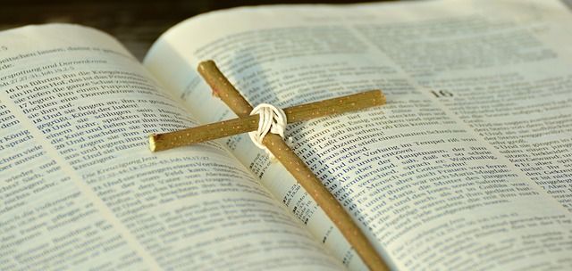 Ein kleines Holzkreuz liegt auf einer aufgeschlagenen Bibel.