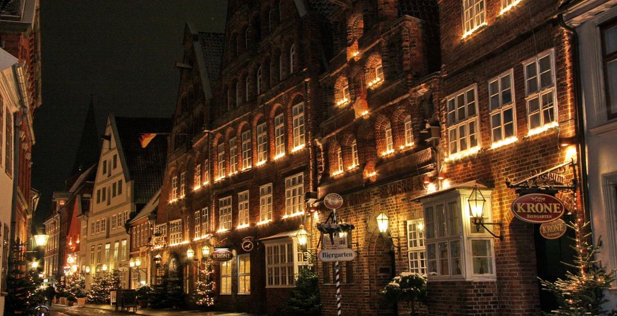 Eine festlich beleuchtete Straße mit historischen Gebäuden und Weihnachtsdekorationen bei Nacht.