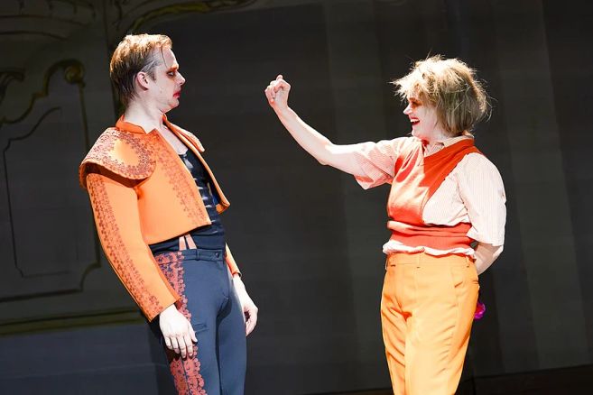 Zwei Schauspieler auf einer Bühne in orangefarbenen Kostümen, eine Szene zu „Clockwork Orange“ nach Anthony Burgess.