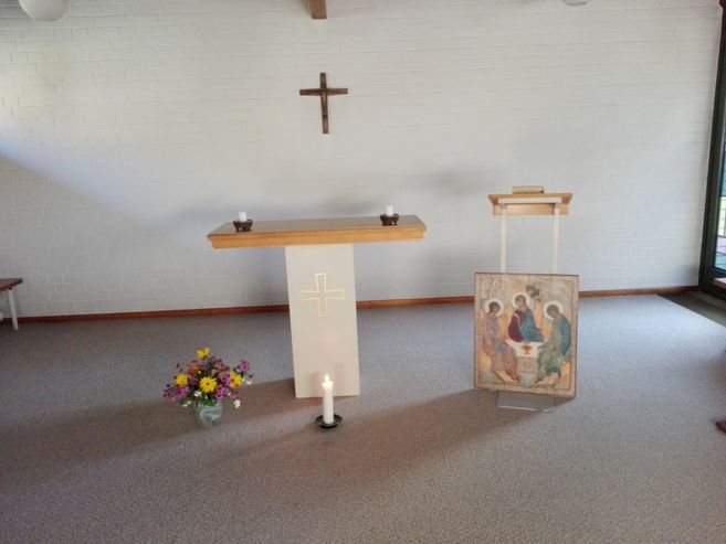 Ein schlichter Altarraum mit Kreuz, Blumenstrauß und Ikone.