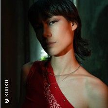 Person in rotem Oberteil mit dunklem Hintergrund.