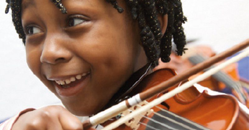 Ein Kind spielt fröhlich Geige und lächelt.