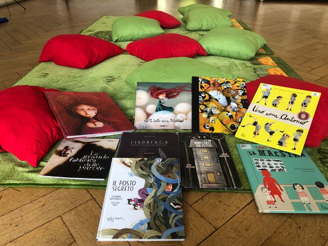 Spielteppich mit bunten Kissen und italienischen Kinderbüchern