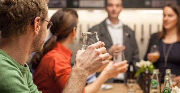 Menschen bei einem Bier-Seminar in Hamburg, die Gläser in der Hand halten.
