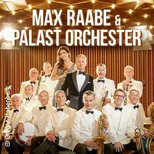 Max Raabe und das Palast Orchester posieren in eleganter Kleidung vor einem hölzernen Hintergrund.