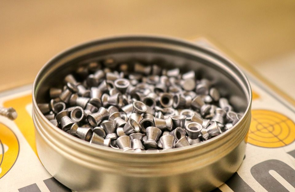 Nahaufnahme einer offenen Dose mit Luftgewehrkugeln auf einer Zielscheibe.