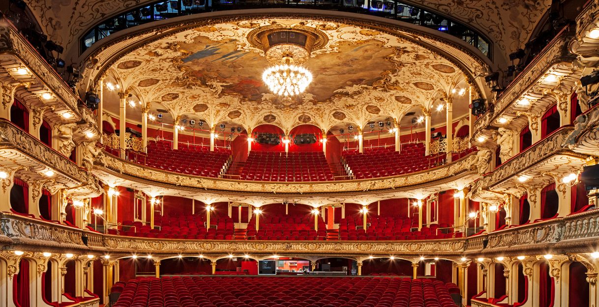 Das Saal des Deutschen SchauSpielHauses aus Sicht der Bühne: Rot bezogene Samt-Sitze und goldener Stuck, in der Mitte der Decke der große Kronleuchter.